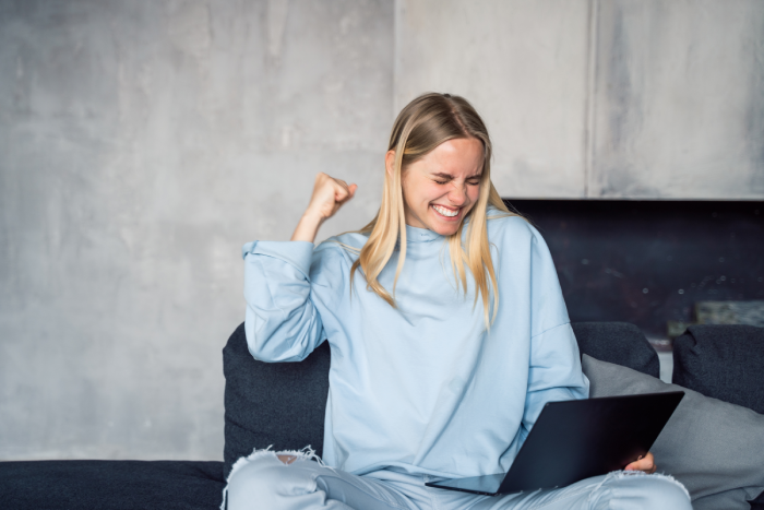 happy-woman-using-silver-laptop-while-sitting-sofa